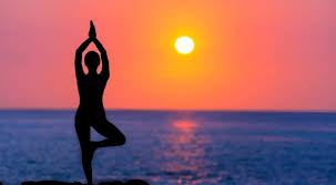 Image of a person exercising yoga on the beach while sunset 