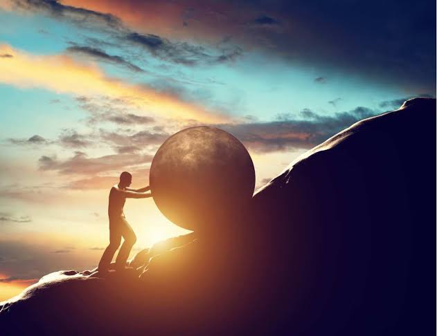 features a man pushing a massive boulder up a steep rugged incline.